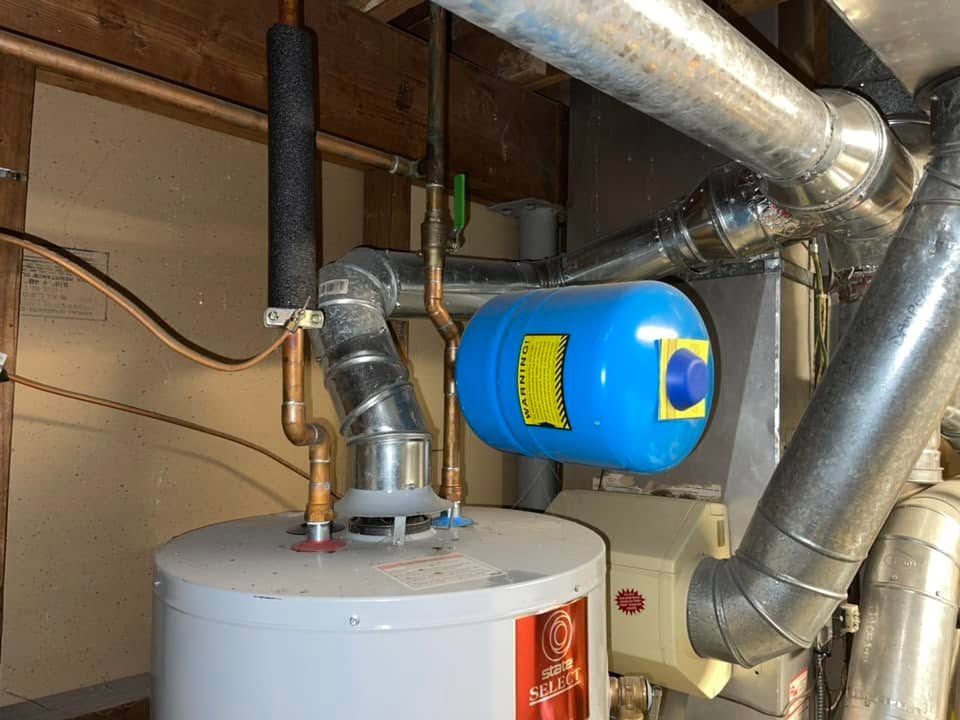 Water heater with new venting and blue expansion tank installed in a basement