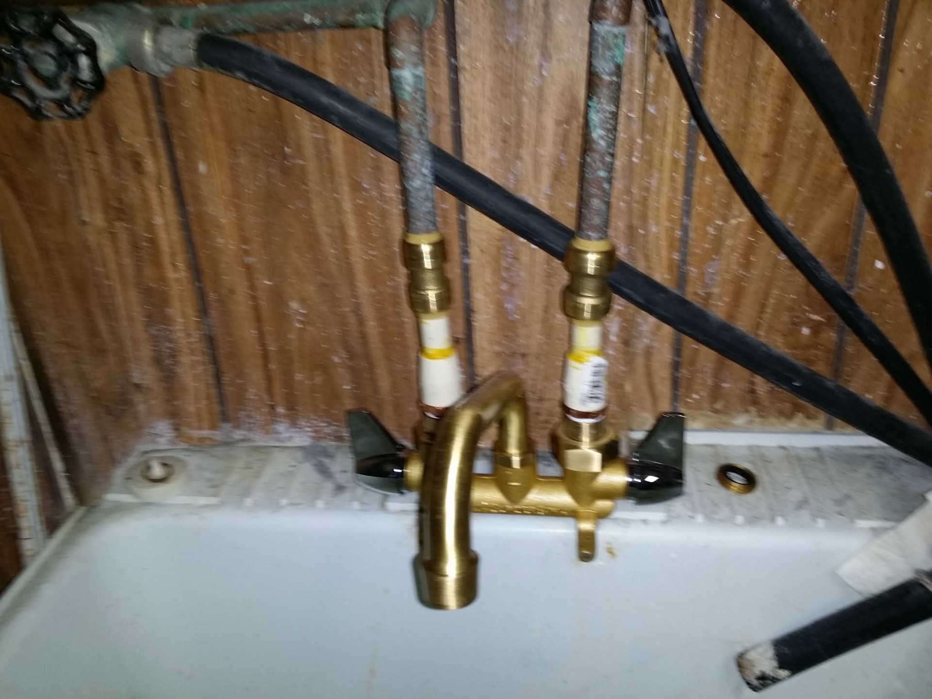 New brass laundry faucet with fresh copper supply lines after plumbing repair